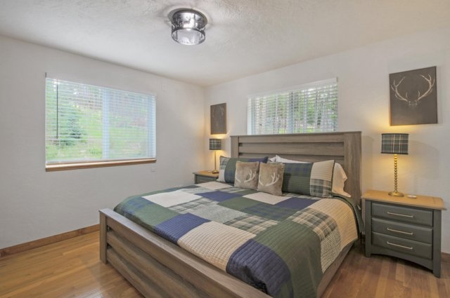Primary bedroom with plaid bedding and forest views